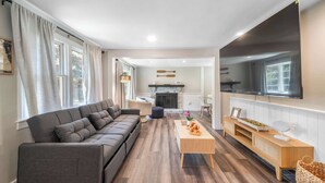 Una sala de estar moderna con un sofá gris, una mesa de centro de madera y un televisor montado en la pared.