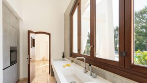 A modern kitchen with a large window, a built-in oven, and a white countertop. - Luxury villa with private pool | Villa Arabesca (Selva di Fasano)