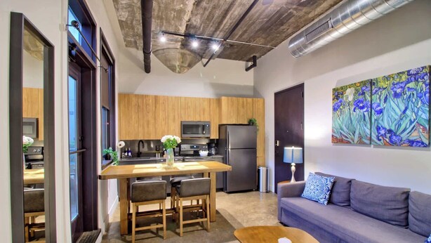 A compact living space with a kitchenette, a sofa, a coffee table, and a painting on the wall.