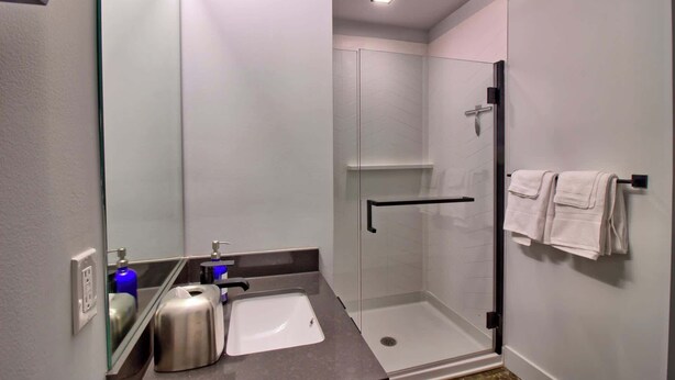 Une salle de bain moderne avec une douche à parois de verre, un lavabo avec un miroir et un porte-serviettes.