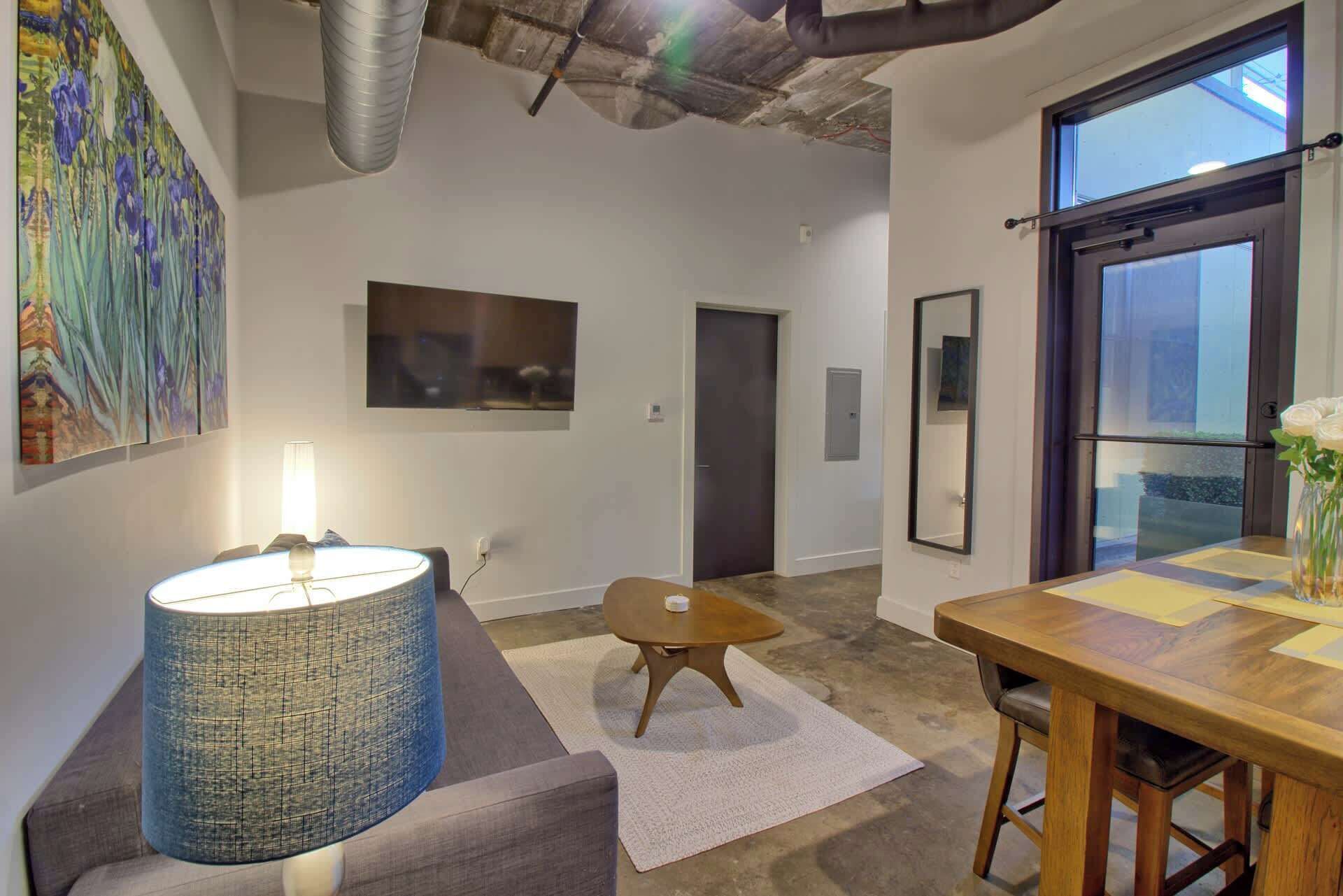 A modern interior with a dining area, a large blue lamp, and a painting on the wall.