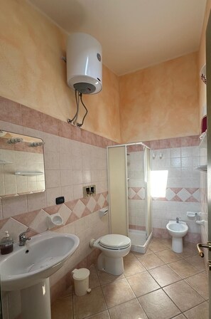 Et badeværelse med vask, toilet, bidét og brusebad.