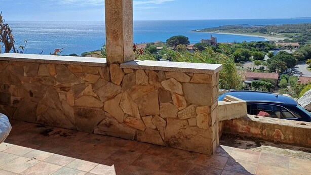 A stone patio with a view of the sea and a distant shoreline.