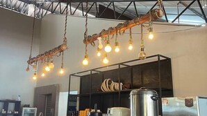 A kitchen area with hanging light fixtures, stainless steel appliances, and a counter. - Arwana Beach Resort - Perhentian (Pulau Perhentian Besar)