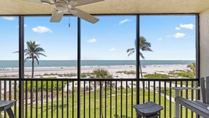 A balcony with a view of the beach, palm trees, and the ocean. - OCEAN'S REACH 3X3: 1-Bdrm, 3rd Floor, Gulf Front Views, All Amenities Open! (Sanibel Island)