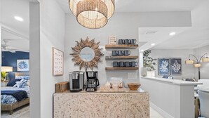 A modern kitchen with a coffee station, a decorative mirror, and a coffee-themed sign. - OCEAN'S REACH 3X3: 1-Bdrm, 3rd Floor, Gulf Front Views, All Amenities Open! (Sanibel Island)