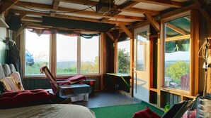 A cozy room with a bed, a desk, and a chair. There are large windows offering a view of the outside. - BlackSea-side base for your European adventure. (Primorsko)