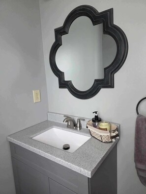 A bathroom with a white sink, a modern faucet, a black mirror frame, and a towel rack. - Quiet Country Cottage with access to 396 acres of Audubon native prairie land (Table Rock)