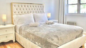 A neatly made bed with a tufted headboard, white bedding, and two bedside lamps.