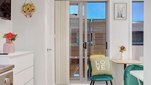 Une cuisine moderne avec des meubles blancs, un four en acier inoxydable et un petit coin repas comprenant une chaise de couleur turquoise et une table.