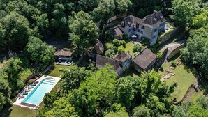 Vista aérea de una extensa propiedad con varias construcciones, piscina y abundante vegetación.