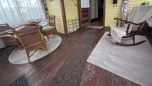 A room with wicker chairs, a rocking chair, a glass table, and a door leading to another room. -  Relax in Classic Style! 3 BR 2 Bath Near the River, Marsh, w/ Game Room & More! (Horicon)