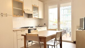 A kitchen with a dining table and chairs, a stove, and cabinets. - RN002 – Rimini, Comfortable Two-Bedroom Apartment Near the Sea with Terrace (Rimini)