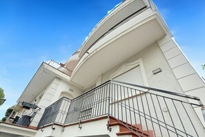 A multi-story building with a balcony, a staircase, and a clear blue sky.