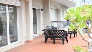 A balcony with a black metal bench, a small table, and a chair. - RN002 – Rimini, Comfortable Two-Bedroom Apartment Near the Sea with Terrace (Rimini)