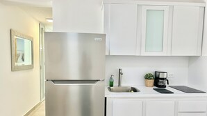 Una cocina moderna con un refrigerador de acero inoxidable, un lavamanos empotrado y una cafetera.