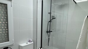 A modern bathroom with a glass-enclosed shower, a toilet, and a window. - LINERLIFE APARTMENT (Málaga)