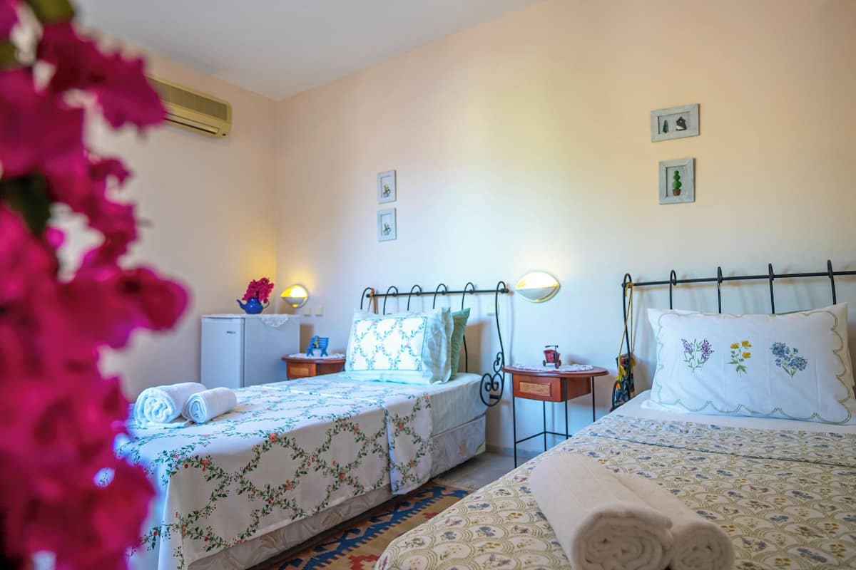 A bedroom with two beds, a small desk, a refrigerator, and a wall-mounted heater.