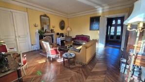 Een ruime woonkamer met een visgraatvloer, een open haard en een grote spiegel.