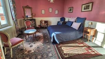Un dormitorio con una cama grande, una araña, un aparador y una silla.