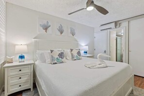 A hotel room with a bed, nightstands, a ceiling fan, and artwork on the wall. - South Kihei resort 1 bedroom condo, AC, across street from beach, walkable area (Wailea-Makena)
