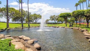 Ein ruhiger Garten mit einem zentralen Wasserspiel, umgeben von üppigem Grün und Palmen.