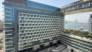 A modern building with a glass facade and a sign reading "NH COLLECTION". - Highend Ultra Luxury with Rooftop Pool (Dubai)