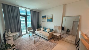 A modern living room with a sofa, armchair, coffee table, and a large mirror. - Highend Ultra Luxury with Rooftop Pool (Dubai)