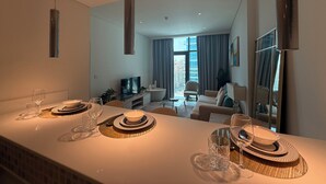 A modern kitchen with a dining area, a TV, and a view of the city. - Highend Ultra Luxury with Rooftop Pool (Dubai)
