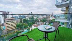 A balcony with artificial grass, a glass table, and wicker chairs. - 2 Bedroom at Skynest Residency Westlands (Nairobi)