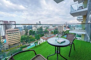 A balcony with artificial grass, a glass table, and wicker chairs. - 2 Bedroom at Skynest Residency Westlands (Nairobi)