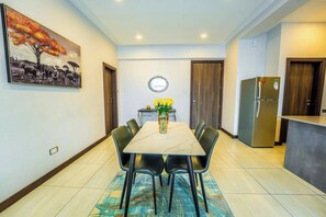 A dining area with a marble table, black chairs, a vase with yellow flowers, and a painting on the wall. - 2 Bedroom at Skynest Residency Westlands (Nairobi)