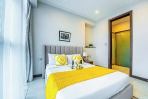 A hotel room with a bed, a nightstand, a framed picture on the wall, and a door to the right. - 2 Bedroom at Skynest Residency Westlands (Nairobi)