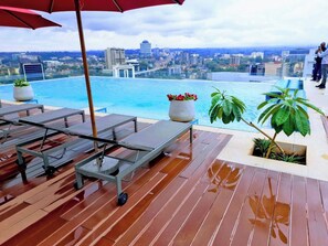 A rooftop pool area with lounge chairs and potted plants, overlooking a cityscape. - 2 Bedroom at Skynest Residency Westlands (Nairobi)