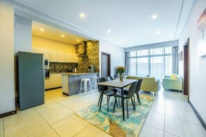 A modern kitchen with a dining area, a large window, and a living space with a sofa and a coffee table. - 2 Bedroom at Skynest Residency Westlands (Nairobi)