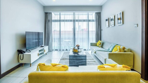A modern living room with a large flat-screen TV, a sofa, and a coffee table. - 2 Bedroom at Skynest Residency Westlands (Nairobi)