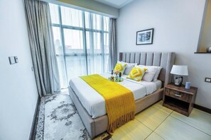 A modern hotel room with a large bed, a bedside table with a lamp, and a view through the window. - 2 Bedroom at Skynest Residency Westlands (Nairobi)