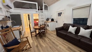 Un espace de vie compact comprenant une chambre en mezzanine, un coin repas et un espace détente avec un canapé.