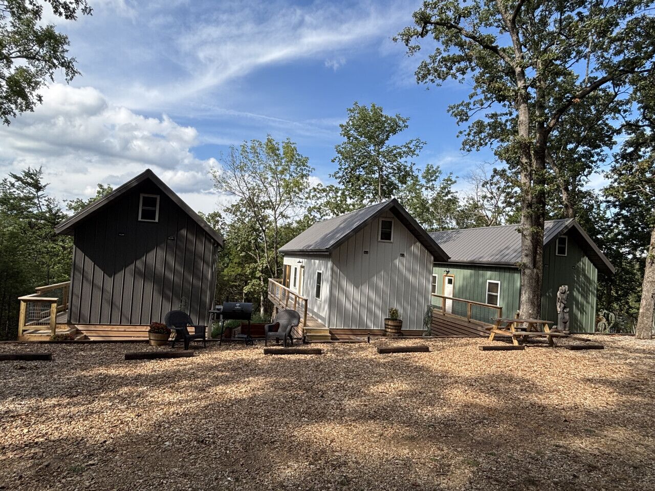 Three cabins with a gravel driveway and picnic tables.