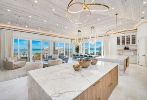 A spacious living area with a large marble island, wooden cabinets, and a view of the ocean. - Tiny Bubbles 30A|Easy Beach Access|Private Pool|Golf Cart (Santa Rosa Beach)