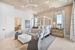 A modern bedroom with a canopy bed, a sofa, a coffee table, and a view of the outdoors. - Tiny Bubbles 30A|Easy Beach Access|Private Pool|Golf Cart (Santa Rosa Beach)