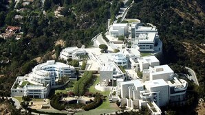 Vista aérea de un moderno complejo arquitectónico con varios edificios, jardines ajardinados y un camino sinuoso.