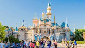 A castle-like structure with multiple towers and flags, surrounded by a crowd of people.