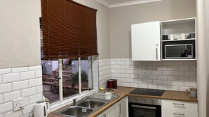 A kitchen with a window, white cabinets, a microwave, and a sink.