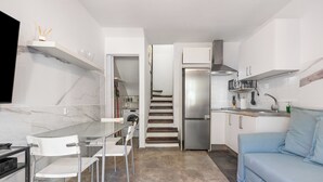 Une cuisine moderne avec un coin repas, un four encastré et un escalier menant à un autre niveau.