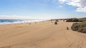 Une vaste plage de sable fin, avec un ciel dégagé et une vue sur l’océan.