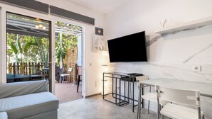 Une cuisine moderne équipée d’un téléviseur, un coin repas avec une table et des chaises, et un canapé.