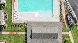Vue aérienne d’une propriété dotée d’une piscine, d’un court de tennis et d’un espace de stationnement.