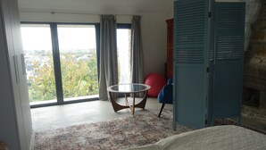 A room with a large window, a round table, a red exercise ball, a blue chair, and a wardrobe.