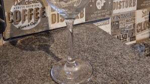 A wine glass on a granite countertop with vintage-themed wall art in the background. - house with WiFi in Guarulhos you can share room and kitchen and hall with tv (Jardim Cristina Guarulhos)